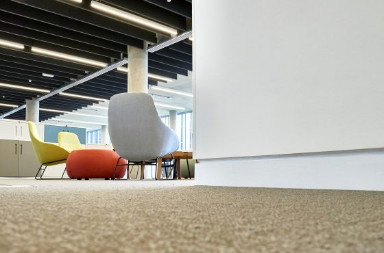 Low angle photo of commercial office space with tables and chairs, view of plaster shadow gap detailing to bottom length of wall