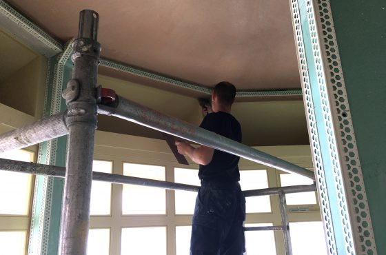 Man on scaffolding applying plaster to internal PVCu render beading around bay window