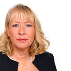 Head shot of lady with blonde hair wearing a pearl necklace and black cardigan on white background