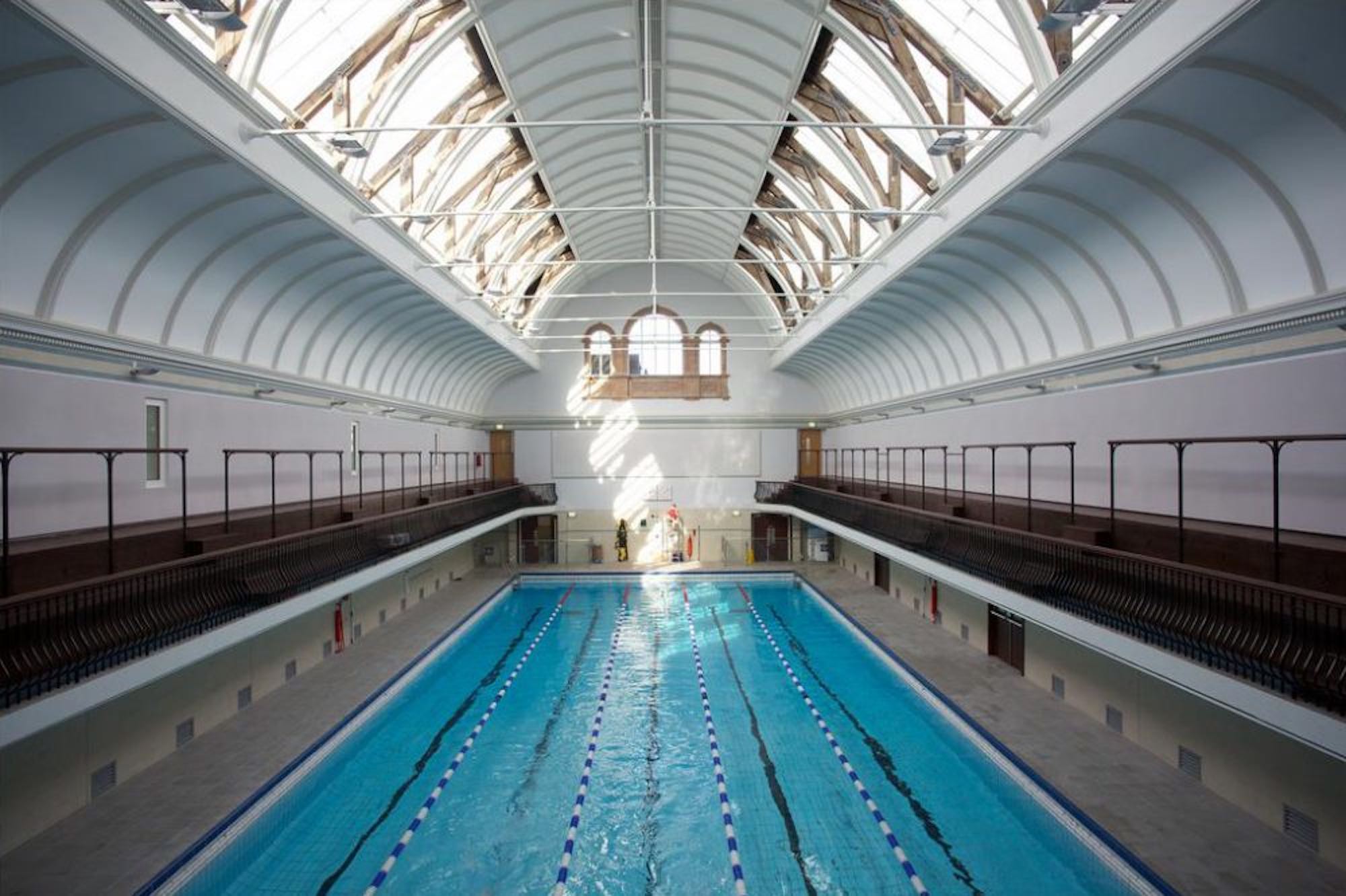 View of length of swimming pool with walk way either side and curved ceiling detail, window to end
