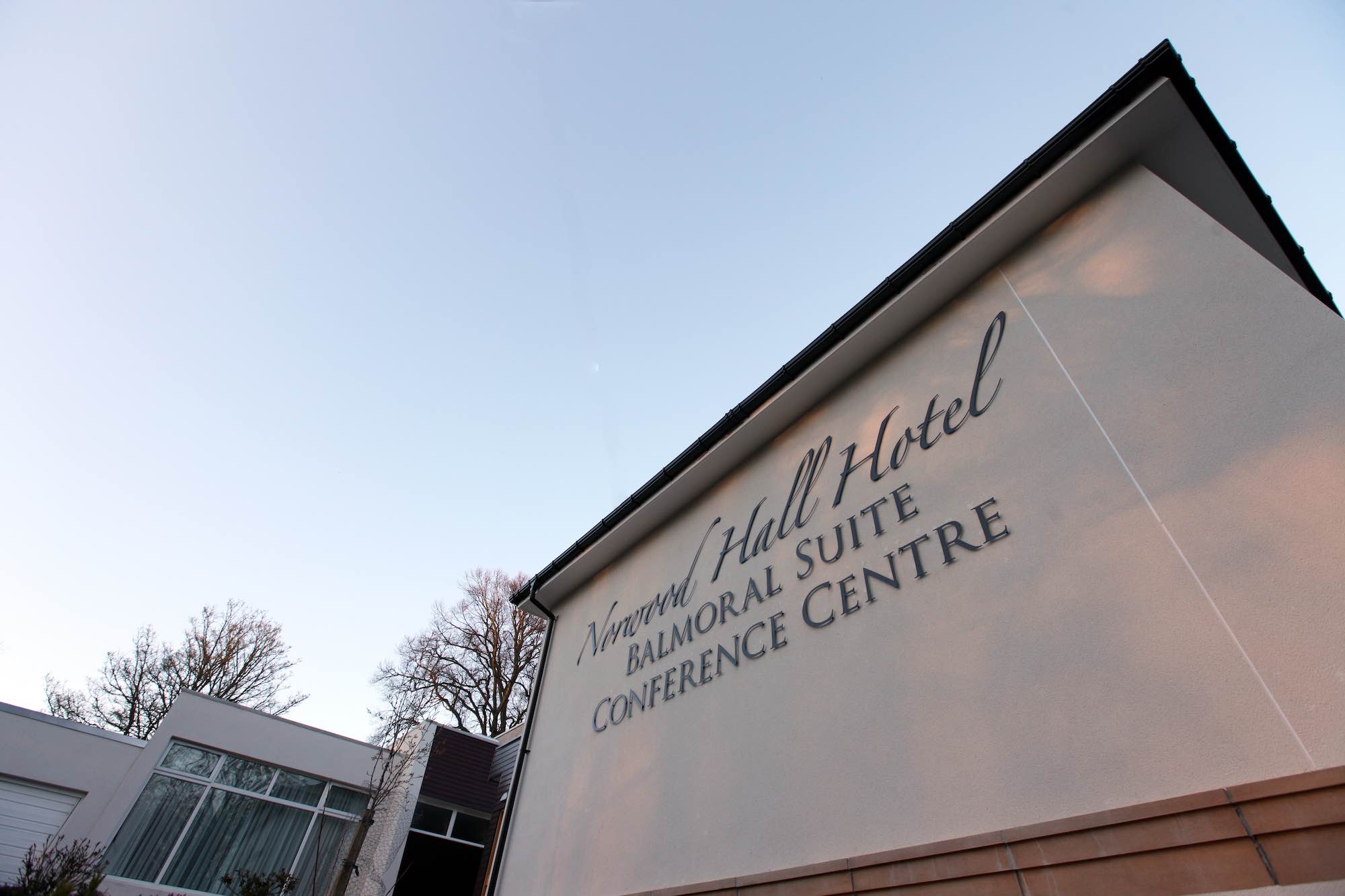Side of building extension with signage on top of render finish with PVCu expansion joint, blue sky