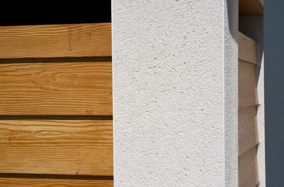 PVCu angle beading with scraped render finish to corner of building next to wooden finish