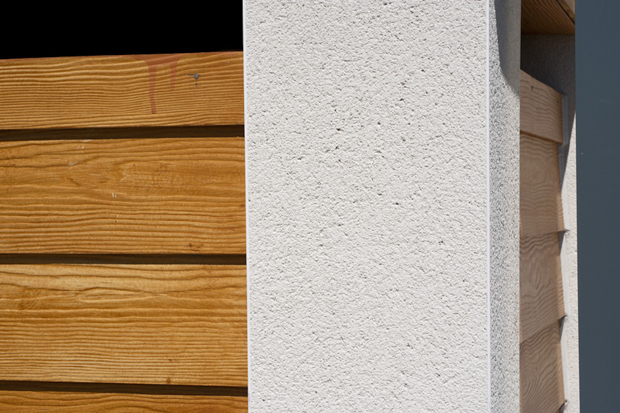 PVCu angle beading with scraped render finish to corner of building next to wooden finish