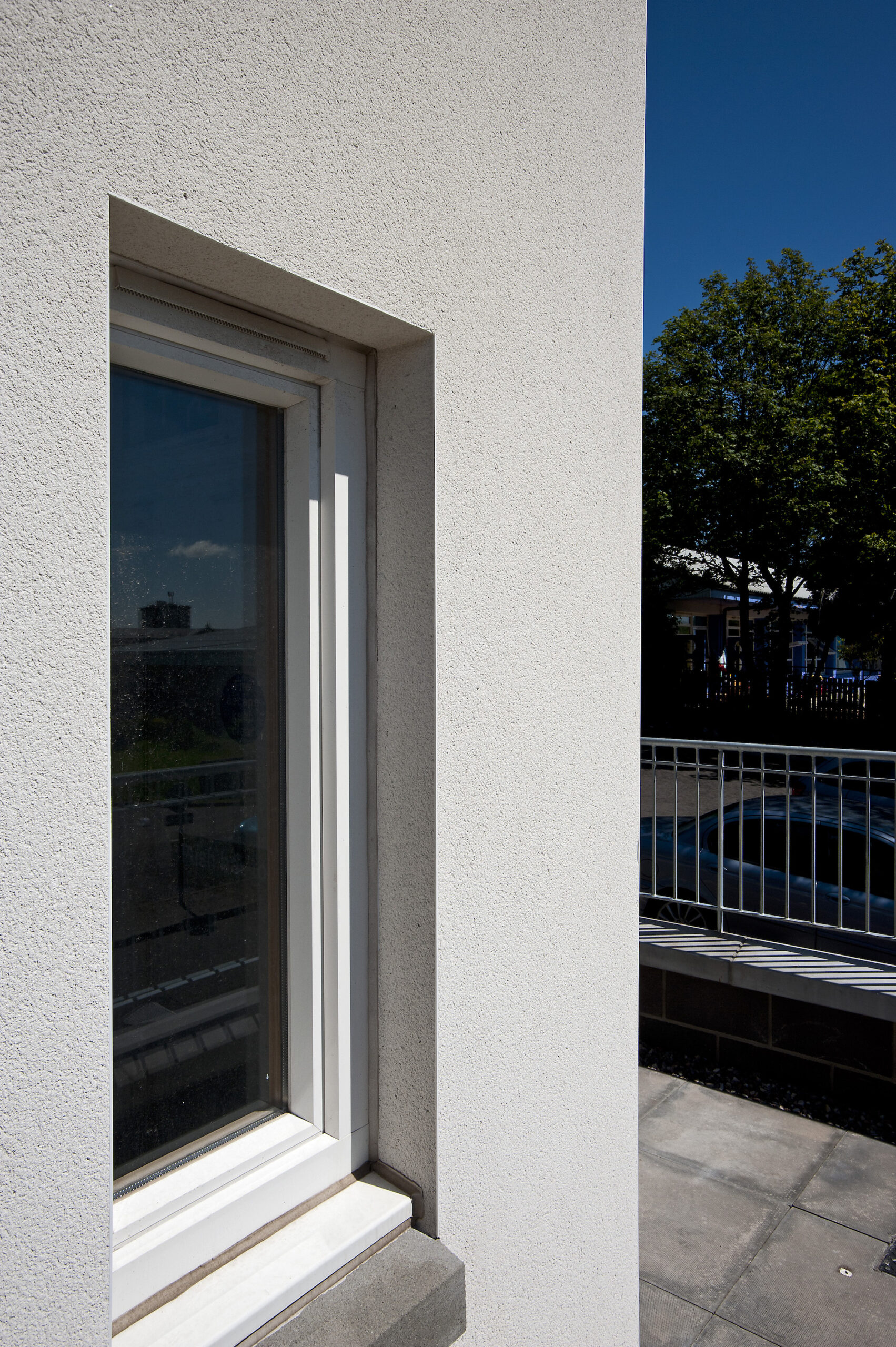 Scraped render finish to building exterior and around window reveal, railing to side of building