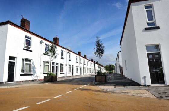 Street with row of houses to either side, rendered finish to all houses and black doors
