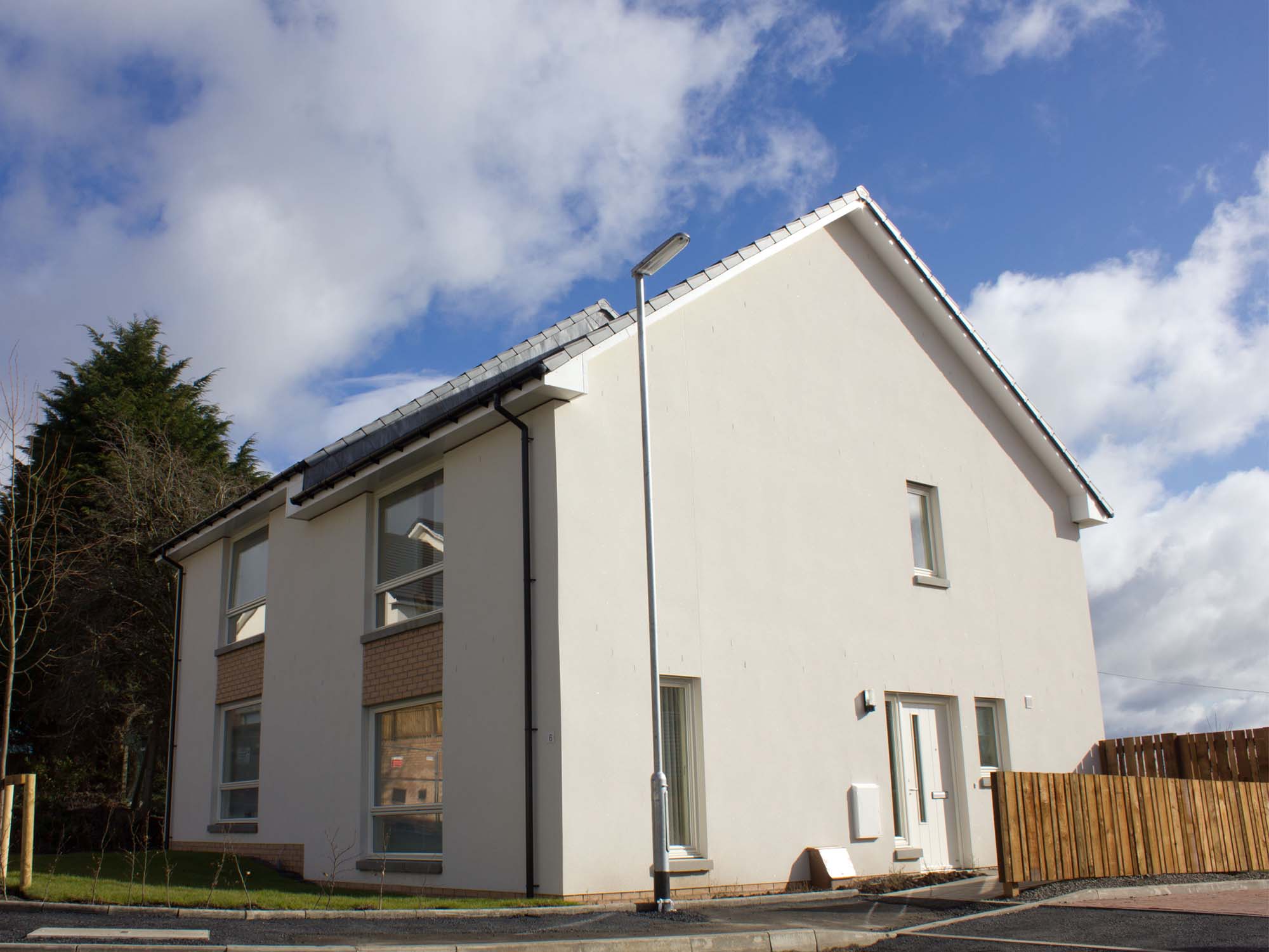 White rendered house with 4 windows to front and door to right hand face of building, fence running along right hand side